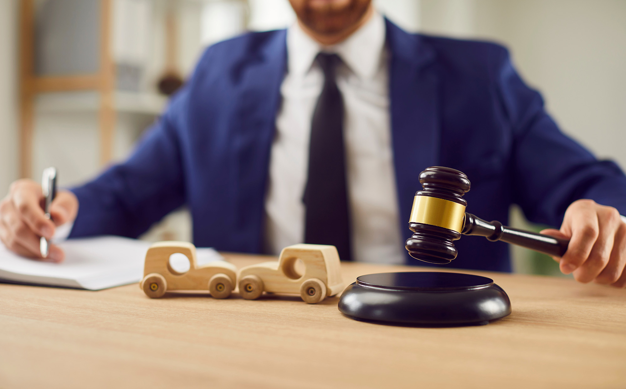 Close Up Shot Of A Lawyer Holds A Gavel Beside Two Toy Cars